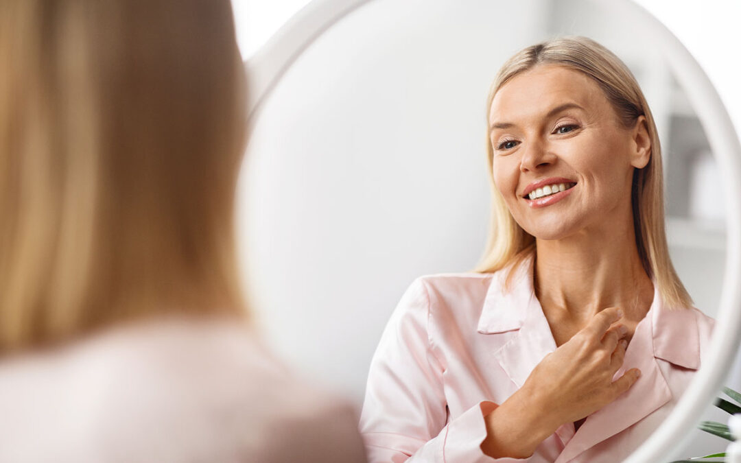 Middle aged woman touching soft skin on neck while looking in mirror
